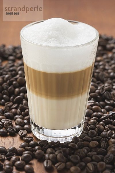 Latte Macchiato im Glas auf Kaffeebohnen