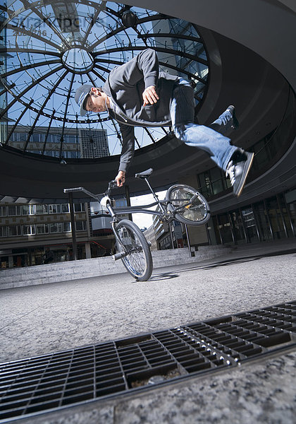 BMX-Fahrer bei akrobatischer Figur im Sprung