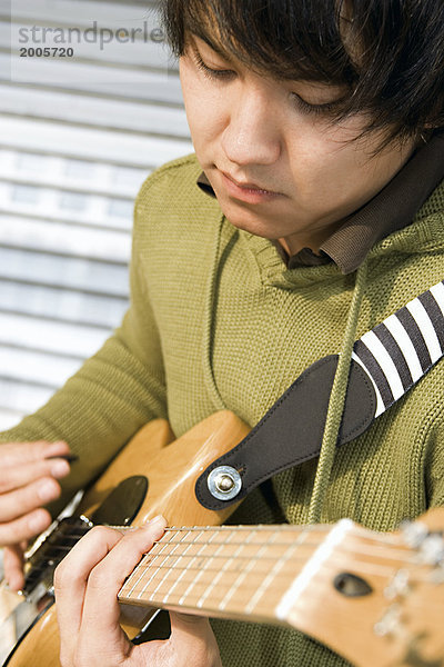 Junger Mann  asiatisch  spielt auf E-Gitarre