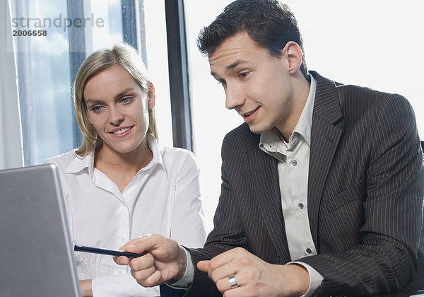 Mann und Frau sitzen im Büro an Laptop