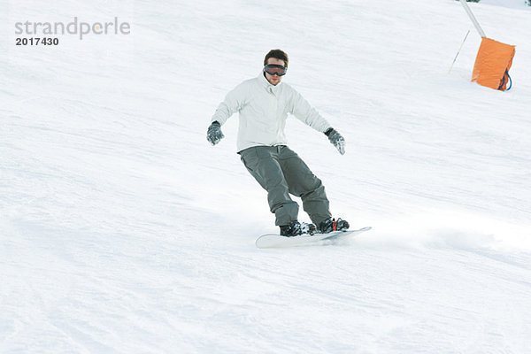 Junger Mann Snowboarden auf der Piste  volle Länge