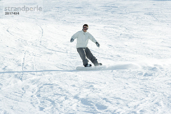 Junger Mann beim Snowboarden auf der Piste  volle Länge