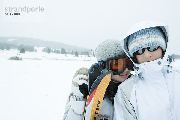 Zwei junge Skifahrer stehen nebeneinander  schauen in die Kamera  der eine mit dem Kopf auf die Schulter.