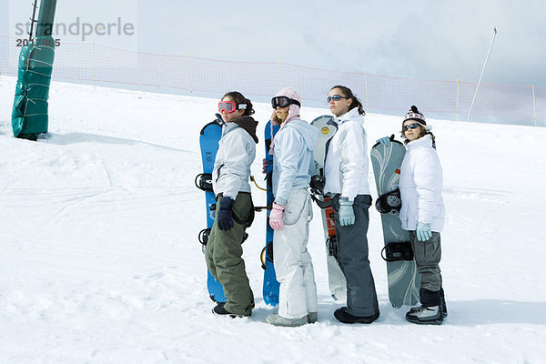 Vier junge Snowboarder stehend  aufgereiht  aufblickend