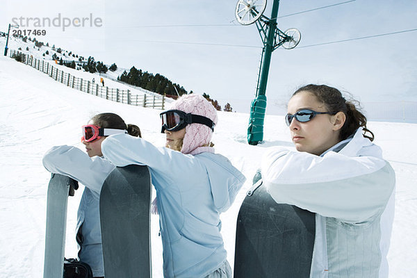 Junge Freunde  die zusammen stehen  Snowboards halten  wegschauen