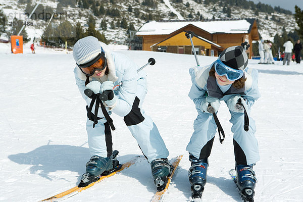 Zwei junge Skifahrer kauern zusammen und schauen in die Kamera.