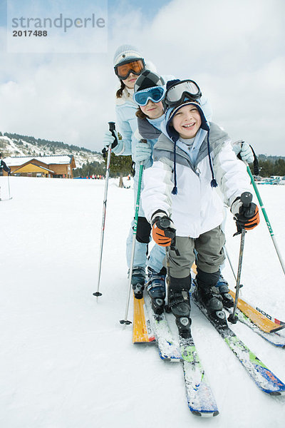 Drei junge Skifahrer stehen zusammen  stehen Schlange  lächeln vor der Kamera