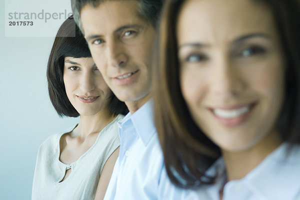 Business-Team in einer Reihe lächelnd auf Kamera  Kopf und Schultern  Fokus auf Frau im Hintergrund  Porträt