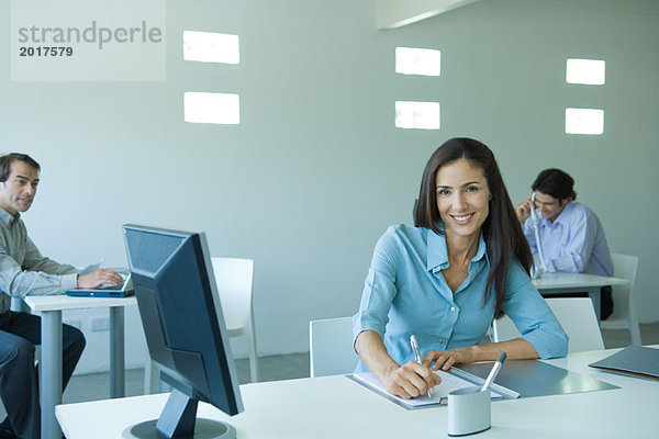 Geschäftsfrau am Schreibtisch sitzend  lächelnd vor der Kamera