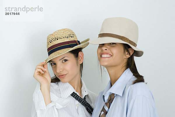 Zwei junge Freundinnen mit Hut und Krawatte  lächelnd vor der Kamera  Porträt