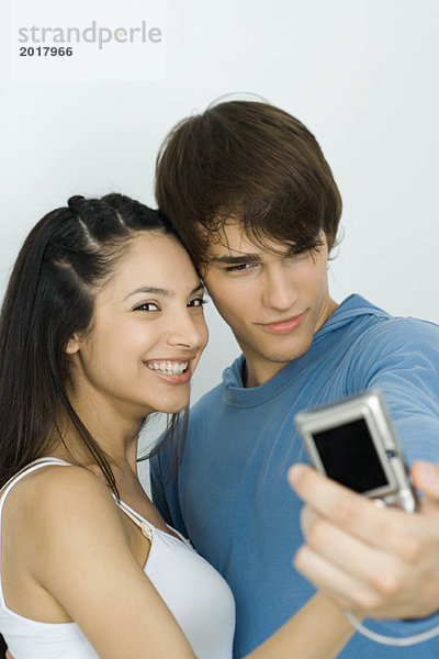 Junges Paar beim Selbstporträt mit Digitalkamera  Frau lächelt in die Kamera