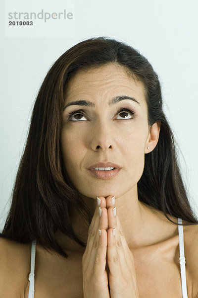 Frau hält Hände im Gebet  schaut nach oben  Porträt