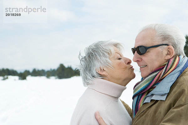 Seniorenpaar stehend von Angesicht zu Angesicht  Küssen  Seitenansicht