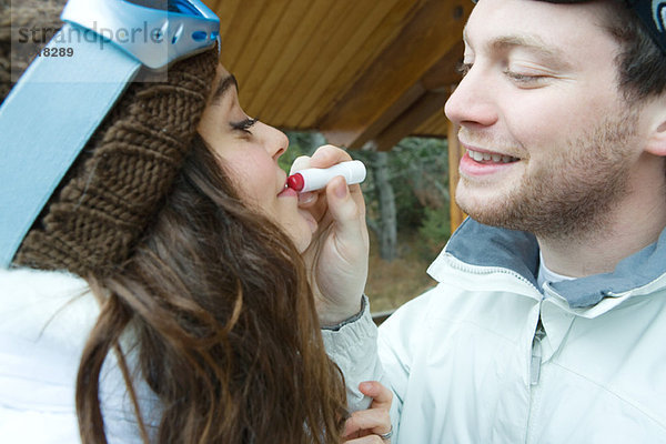 Junger Mann mit Lippenstift auf die Lippen der Freundin  Seitenansicht  Mund