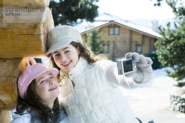 Teenager-Mädchen hält Digitalkamera  fotografiert sich selbst mit Freund  beide lächelnd