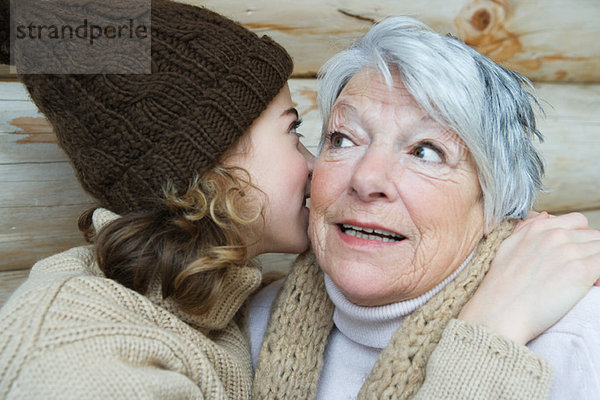 Teenagermädchen flüstert Großmutter ins Ohr  Porträt