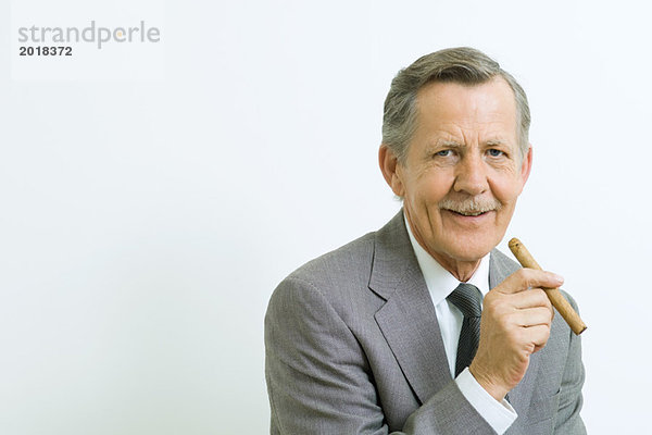 Senior Geschäftsmann lächelt vor der Kamera  hält Zigarre  Porträt