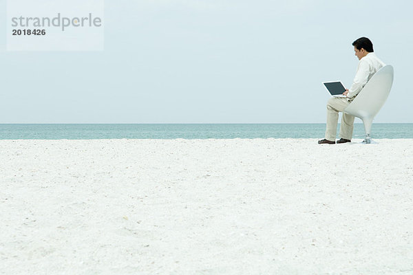 Mann mit Laptop am Strand  volle Länge