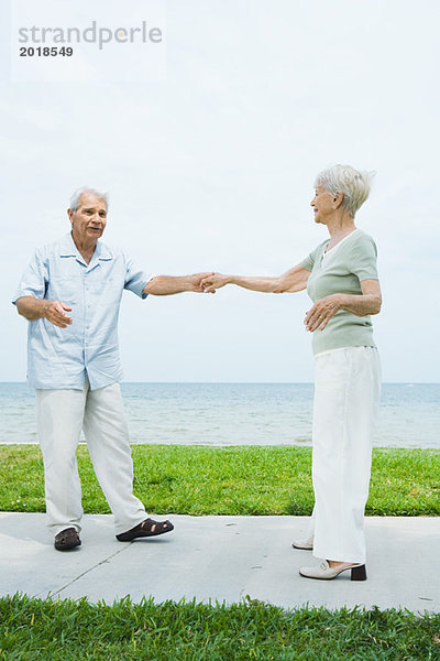 Seniorenpaar tanzt auf dem Bürgersteig mit Blick auf den Ozean  volle Länge