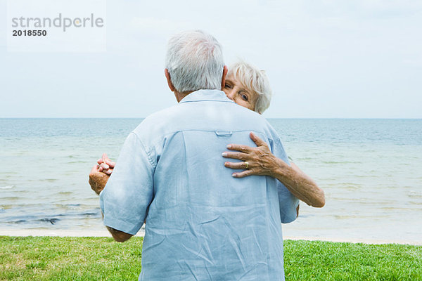 Seniorenpaar tanzt auf dem Bürgersteig mit Blick auf den Ozean  Taille oben