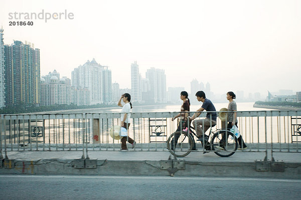 China  Provinz Guangdong  Guangzhou  Radfahrer und Fußgänger über die Brücke  Wolkenkratzer in der Ferne