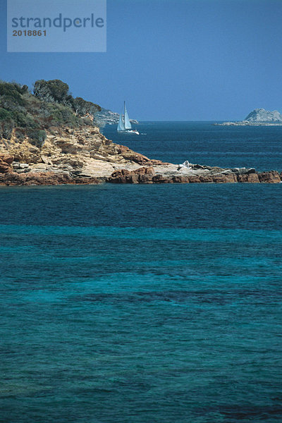 Korsika  Segelboot entlang der Küste  türkisfarbenes Meer im Vordergrund