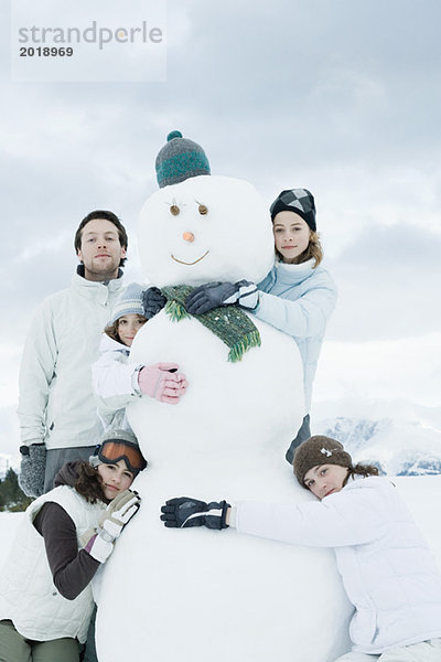 Junge Freunde gruppiert um Schneemann  posieren  Portrait