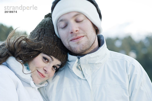 Junges Paar in Skikleidung  junge Frau ruht Kopf auf der Schulter des Freundes