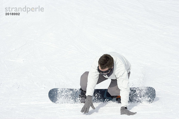 Junger Mann auf dem Snowboard umstürzend  volle Länge