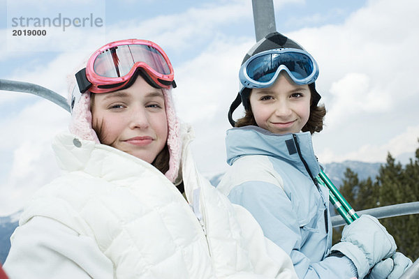 Teenagermädchen und jüngere Freundin beim Skiliftfahren  Portrait