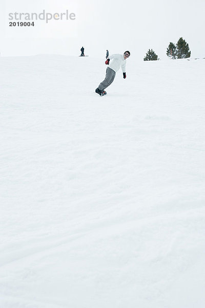 Junger Mann Snowboarden  volle Länge