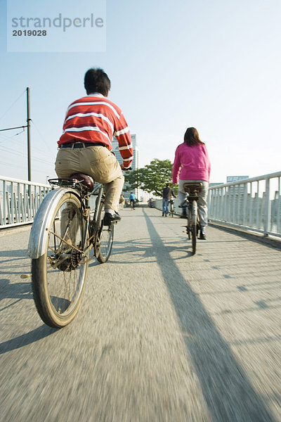 Radfahrer überqueren Brücke  Rückansicht