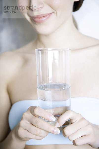 Ausschnitt einer Frau  die ein Glas Wasser hält  lächelnd