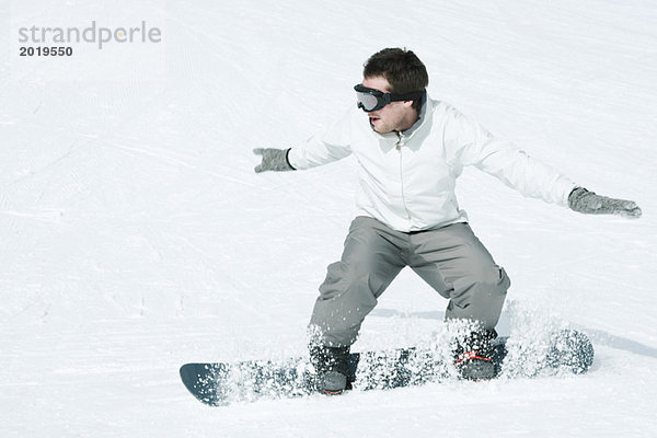 Junger Mann Snowboarden  Action-Shot  volle Länge