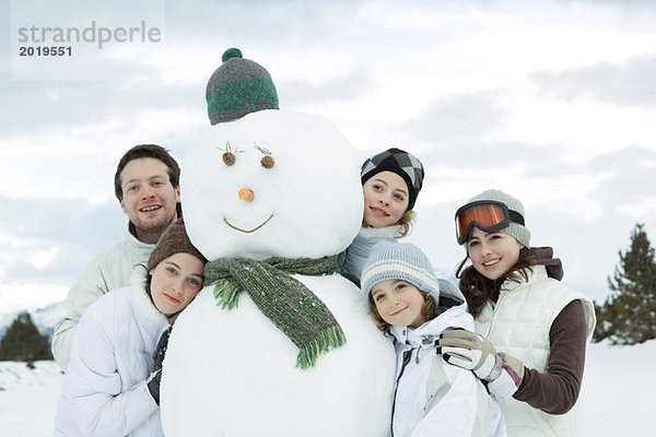 Gruppe junger Freunde um den Schneemann versammelt