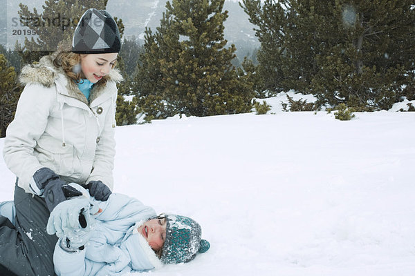 Zwei Teenagermädchen spielen im Schnee.