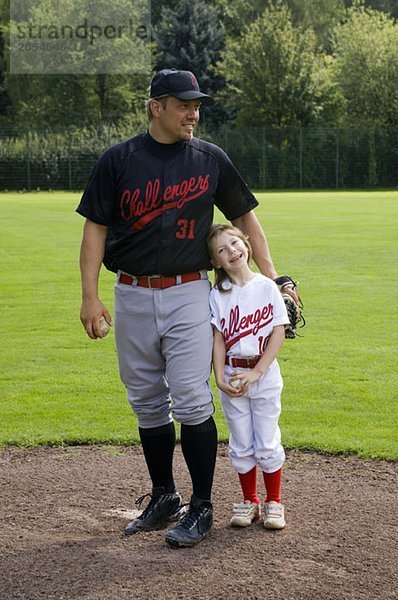 Ein Baseballspieler  der mit seiner Tochter steht.