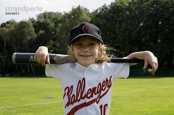 Ein junges Mädchen hält einen Baseballschläger auf ihren Schultern.