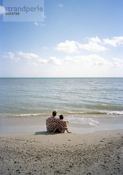 Ein Paar  das zusammen am Strand sitzt.