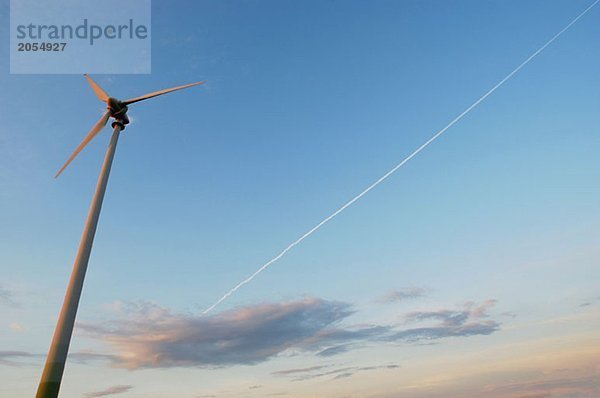 Eine Windkraftanlage und ein Kondensstreifen am Himmel