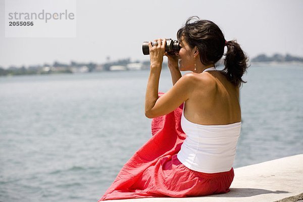 Seitenansicht einer Frau mit einem Fernglas am Meer