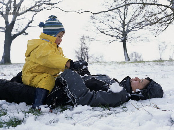 Eine Mutter und ein Sohn spielen zusammen im Schnee.