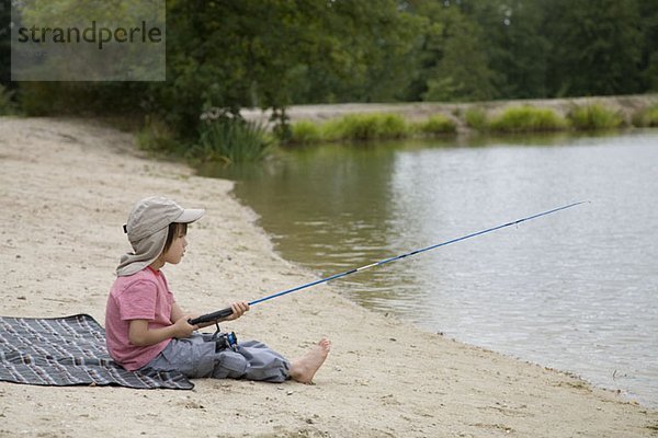 Ein Junge beim Fischen am Strand