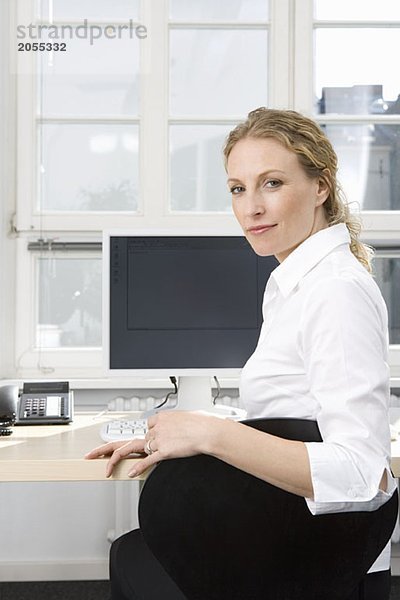 Eine Geschäftsfrau sitzt am Schreibtisch.