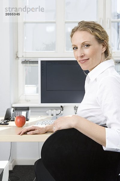 Eine Geschäftsfrau sitzt am Schreibtisch.