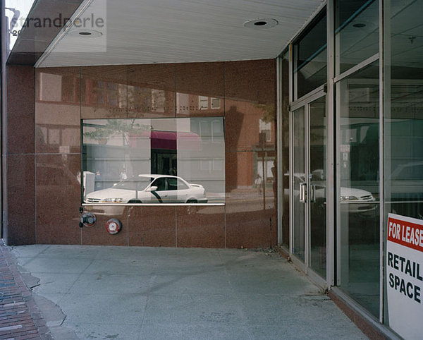 Ein Auto reflektiert in einer glänzenden Gebäudefassade