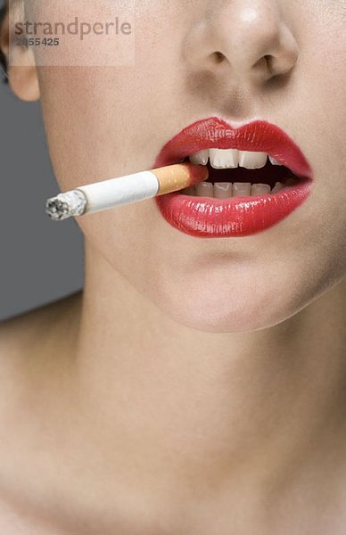 Eine Frau mit rotem Lippenstift und einer Zigarette.