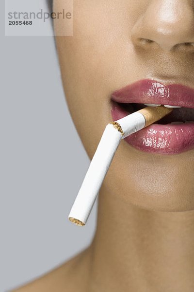 Eine Frau mit einer kaputten Zigarette im Mund.