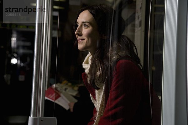 Eine Frau sitzt in einer U-Bahn und lächelt.