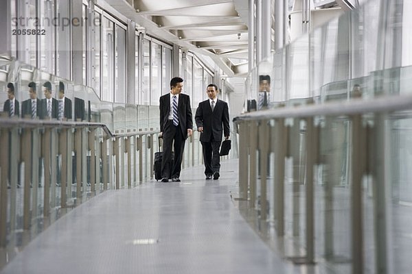 Zwei Geschäftsleute  die einen Korridor entlang gehen.